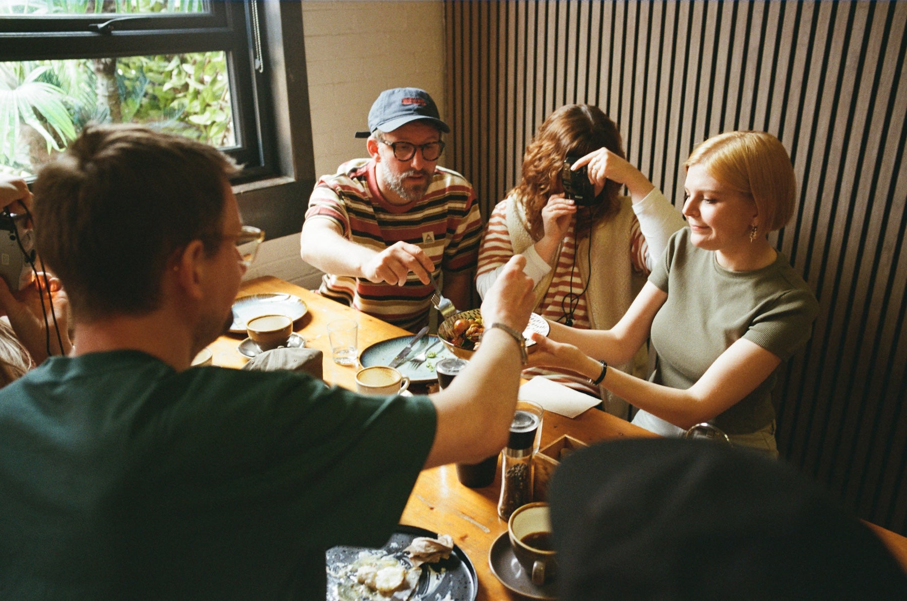 Group of people sitting around a table in a casual setting, in a coffee shop